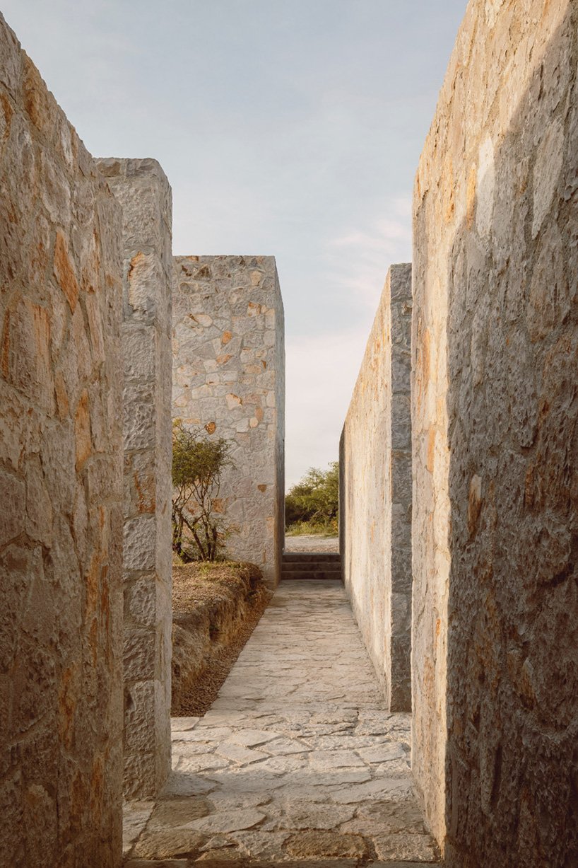 dispersed stone volumes and alleys develop a cruciform residential plan in mexico