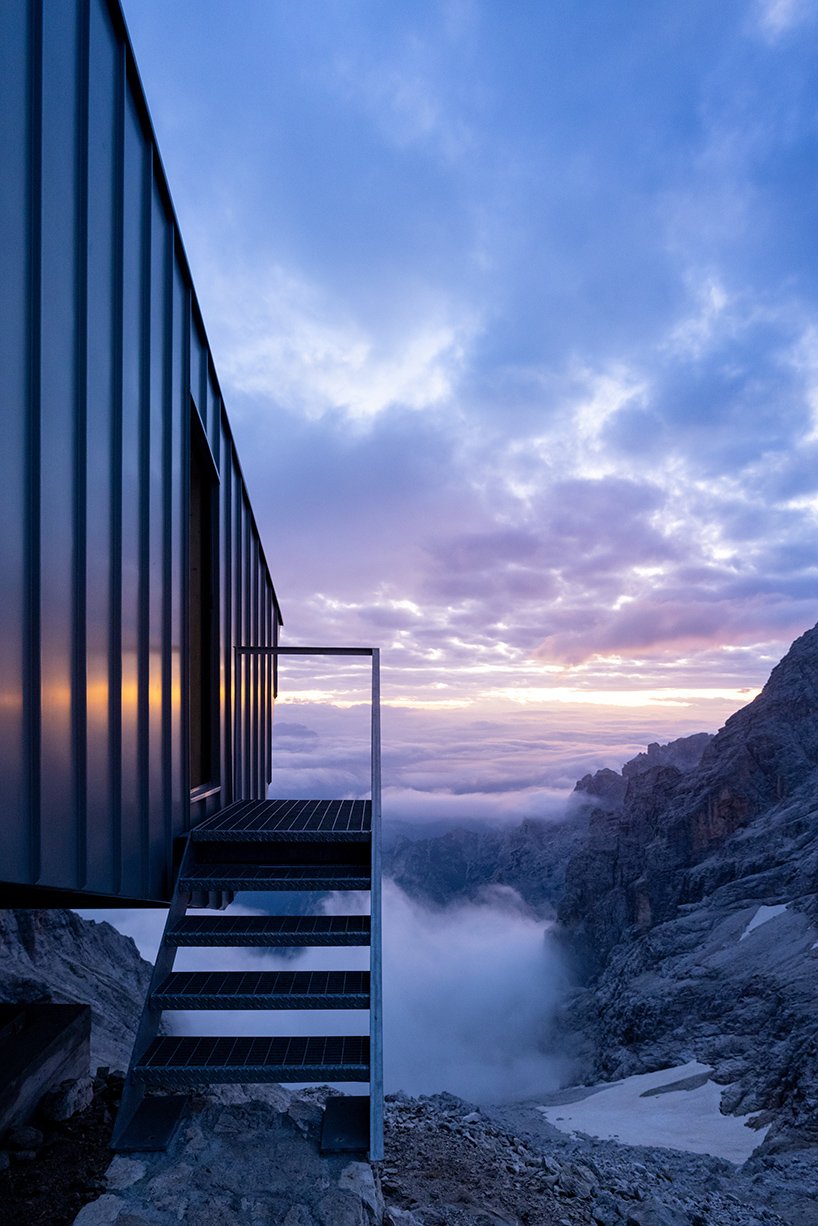 this rough-hewn inclined cabin is suspended on a cliff in the italian dolomites
